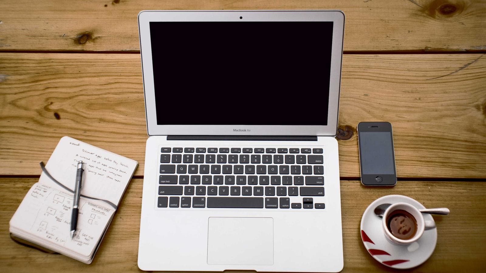 Schreibtisch von oben mit Laptop und Notizbuch voller Oberflächen-Skizzen