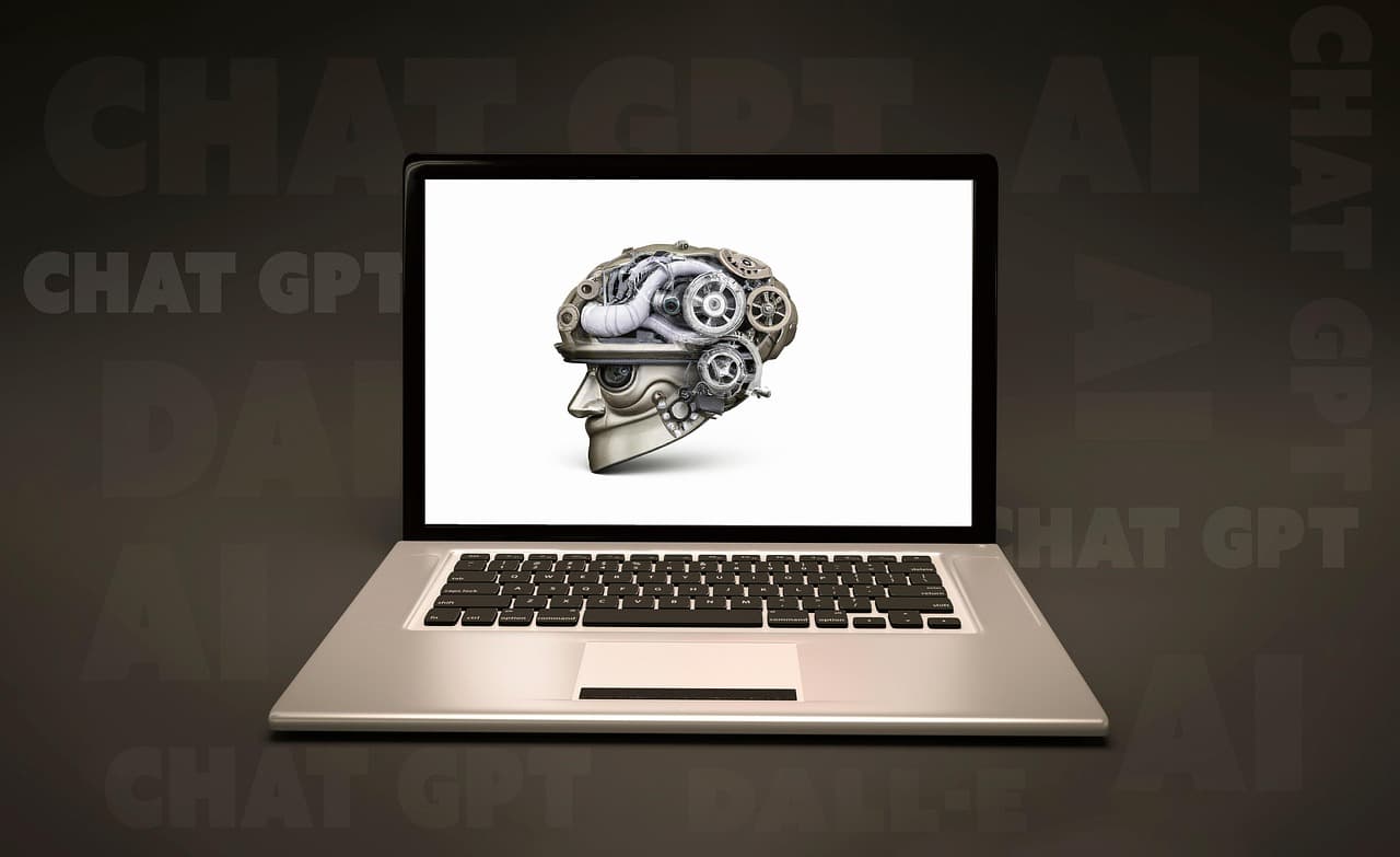 Laptop mit einem mechanischen Gehirn auf dem Bildschirm, im Hintergrund die Schriftzüge »Chat GPT« und »AI« — Sinnbild für KI-generiertes Webdesign